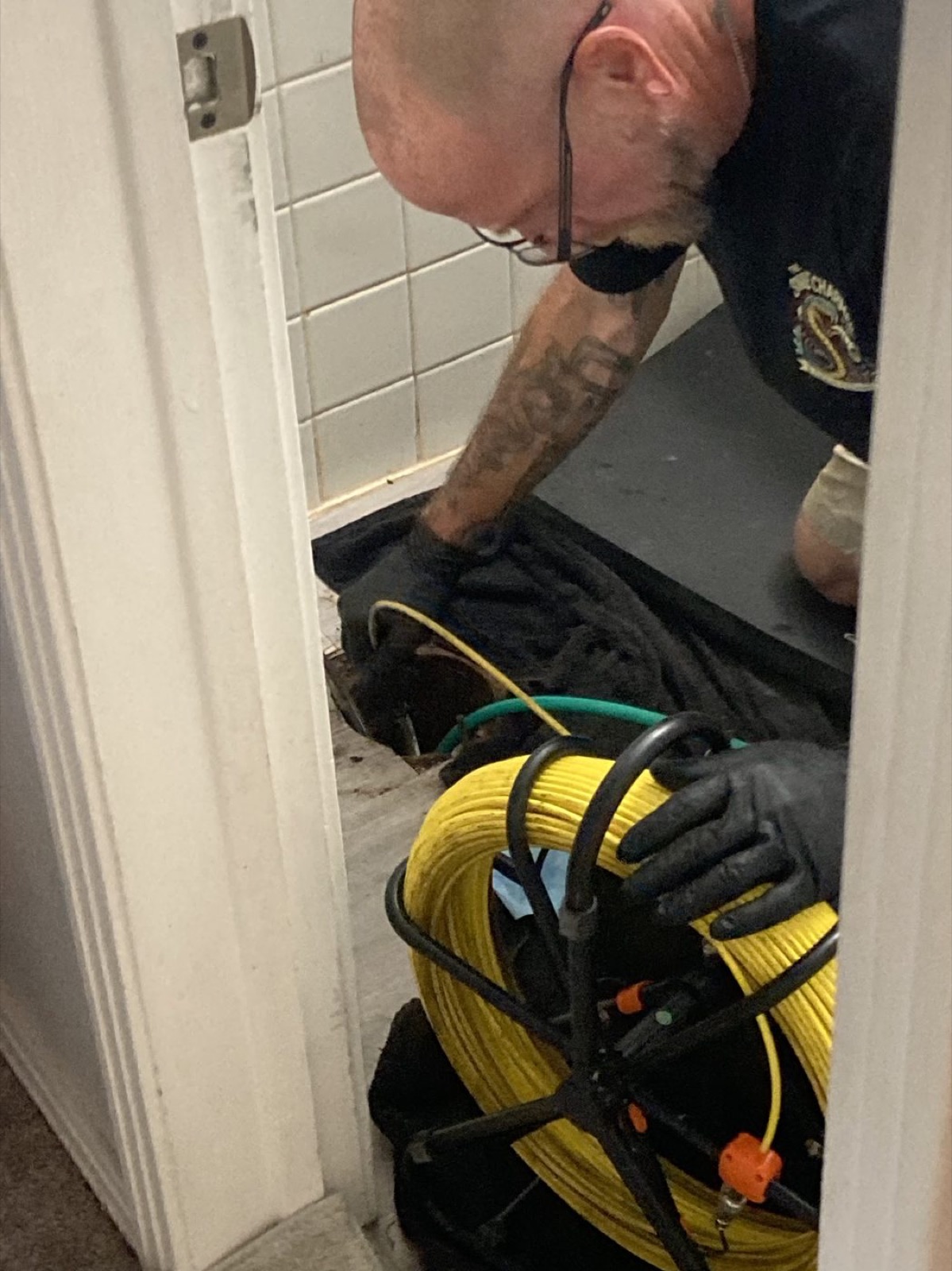 Drain technician feeding camera-inspection equipment into a bathroom drain line